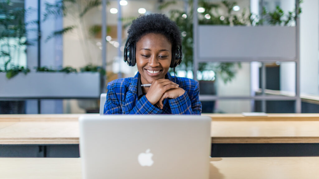 A lady wearing headphones and using her laptop.