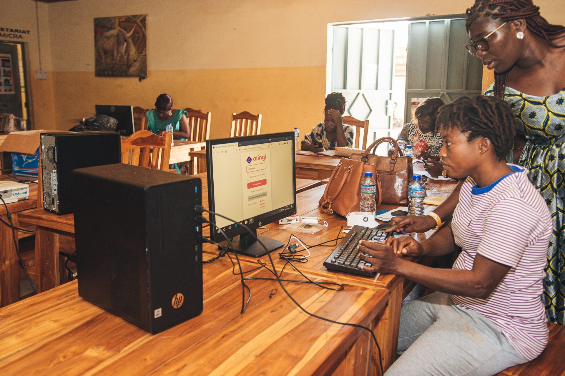 Woman helping another woman to register on atingi