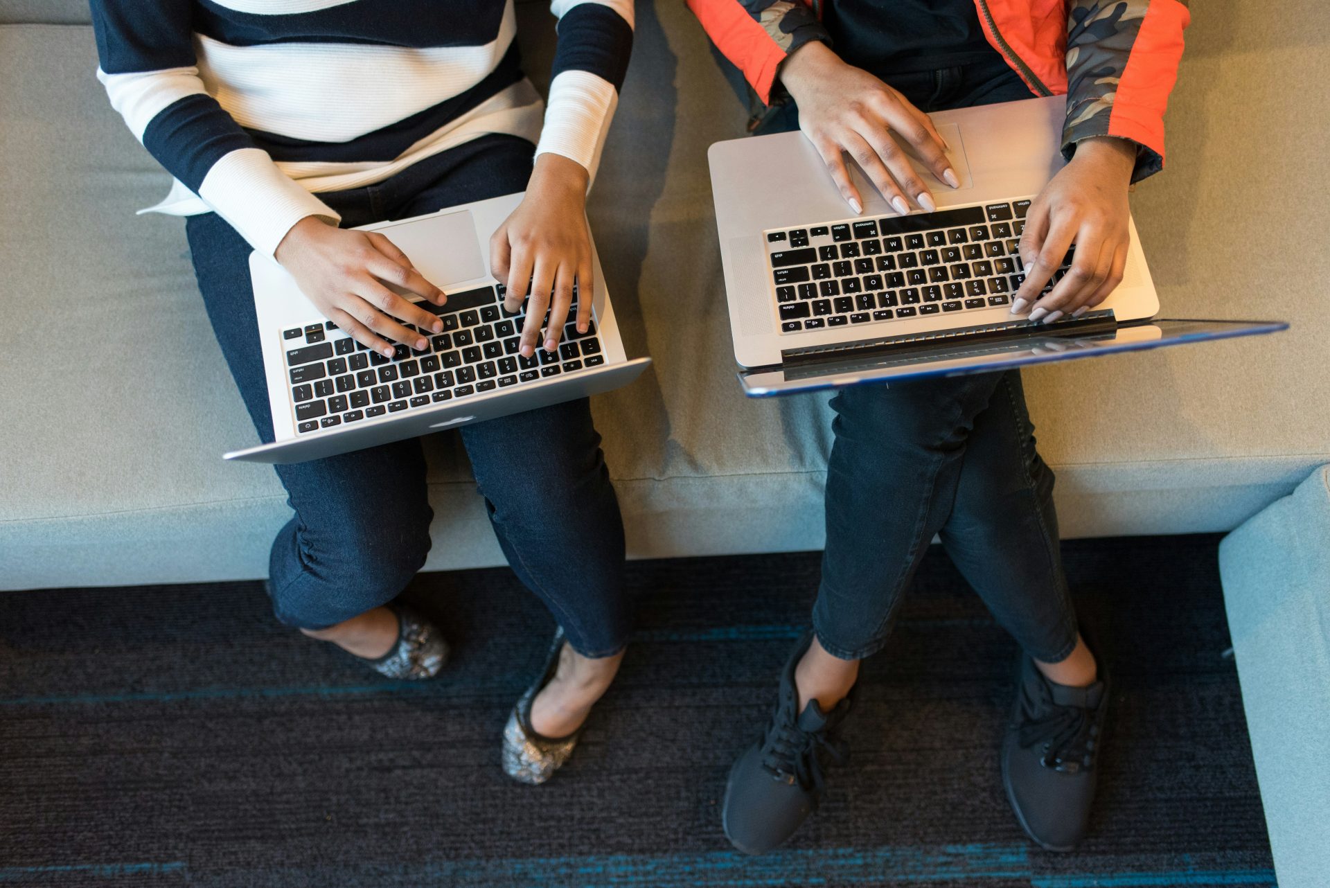 Two women with laptops sitting together seen from above